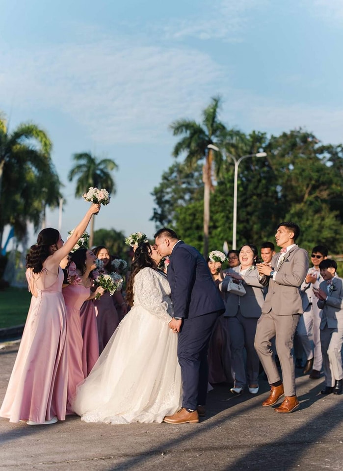 Newlyweds with bridesmaids in elegant pink gowns and groomsmen in dashing gray suits