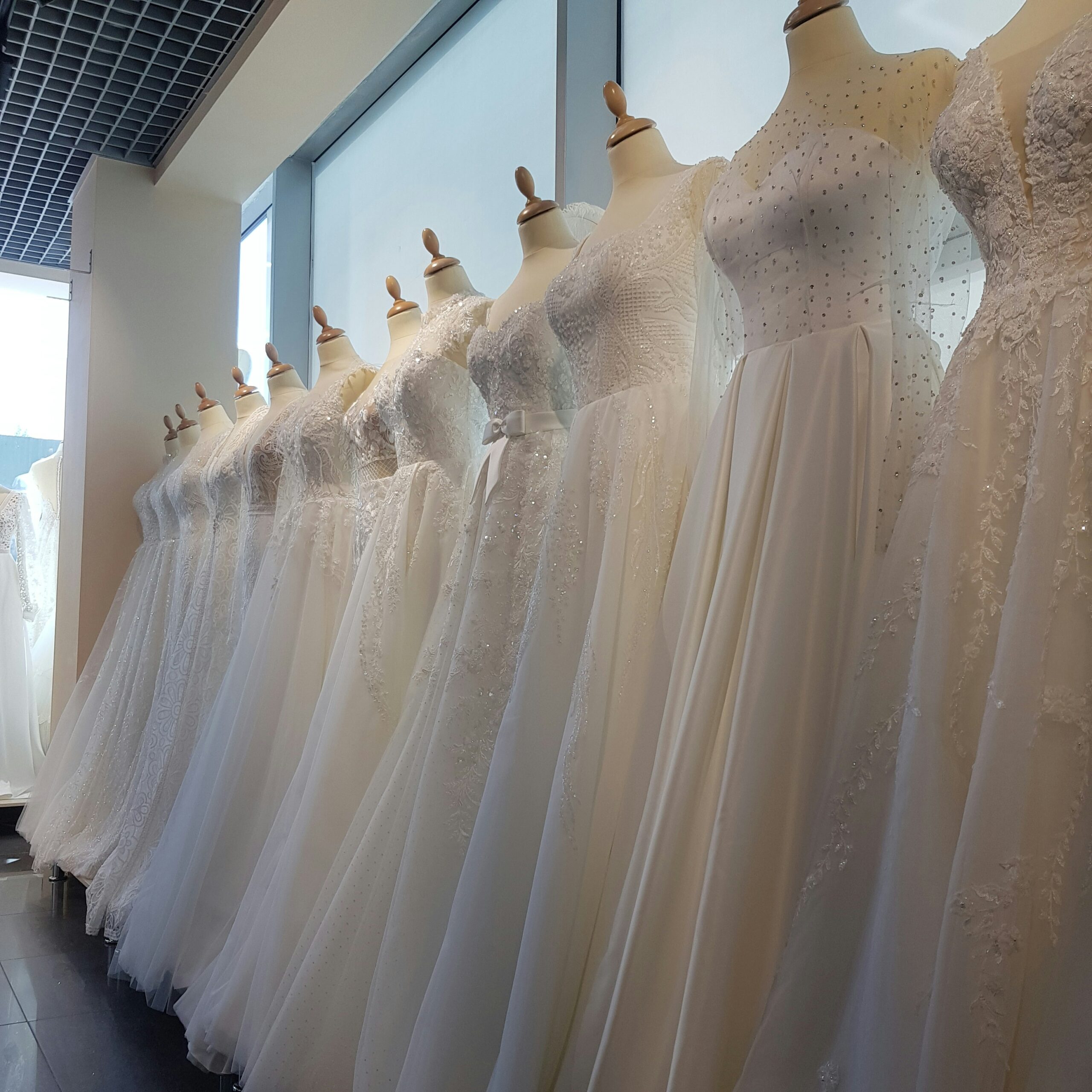 A row of white wedding dresses displayed on mannequins in a bridal boutique