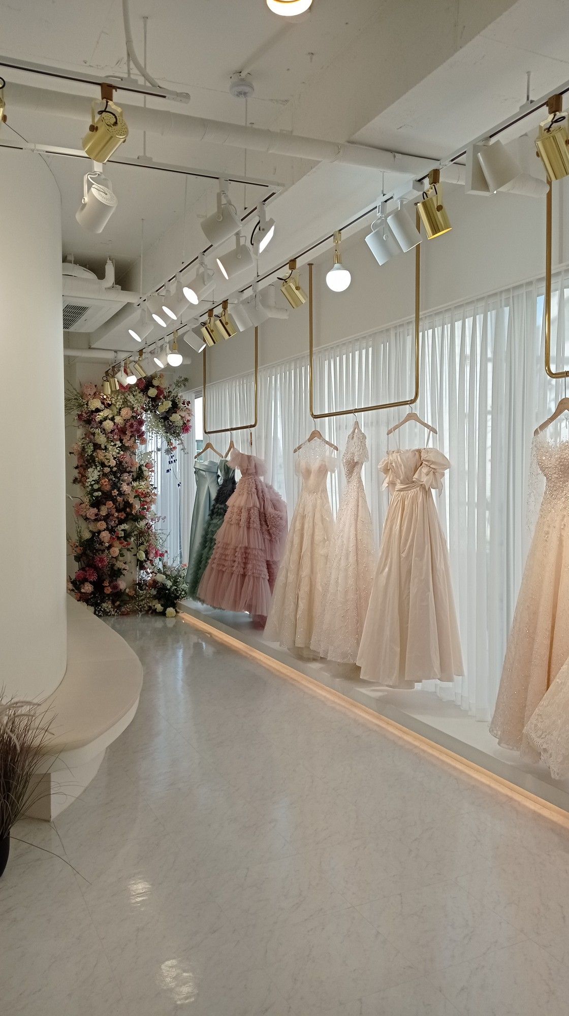 Elegant wedding and debut gowns displayed on modern gold racks inside a minimalist bridal boutique in Pampanga.